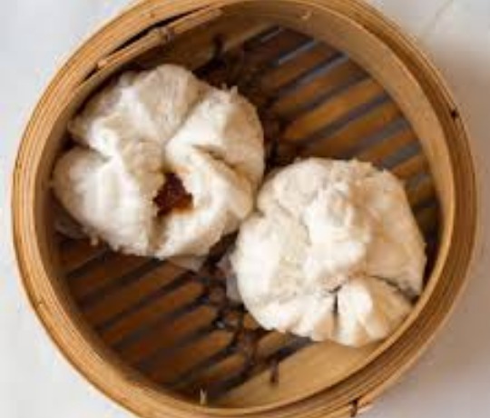 Two BBQ steamed buns in a steamer basket