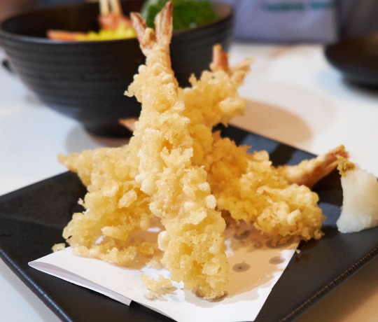 Tempura battered prawn starter arranged on a black plate