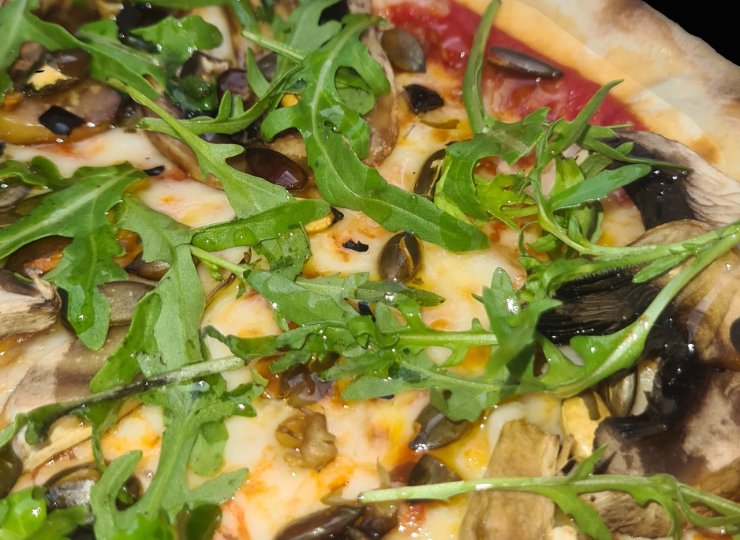 The best pizza from Two Kitchens Loughton Close up image of a pizza, scattered with rocket